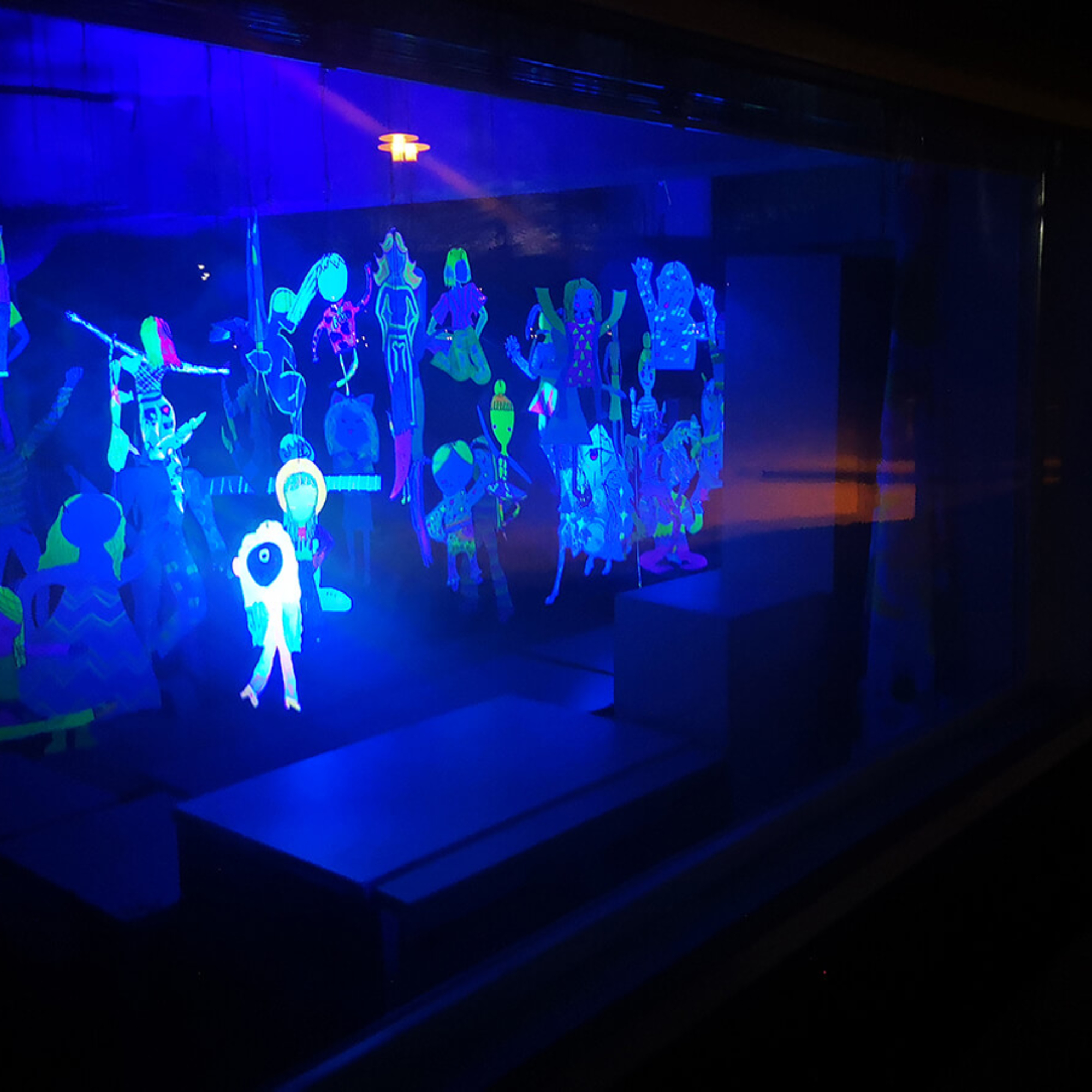 UV-valossa hehkuvia tanssivia ihmishahmoja.