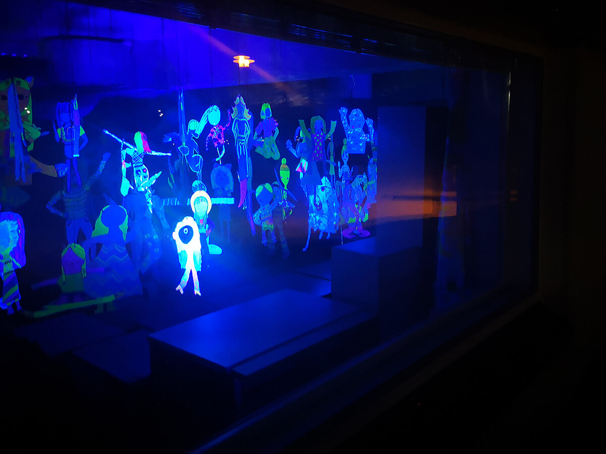 UV-valossa hehkuvia tanssivia ihmishahmoja.