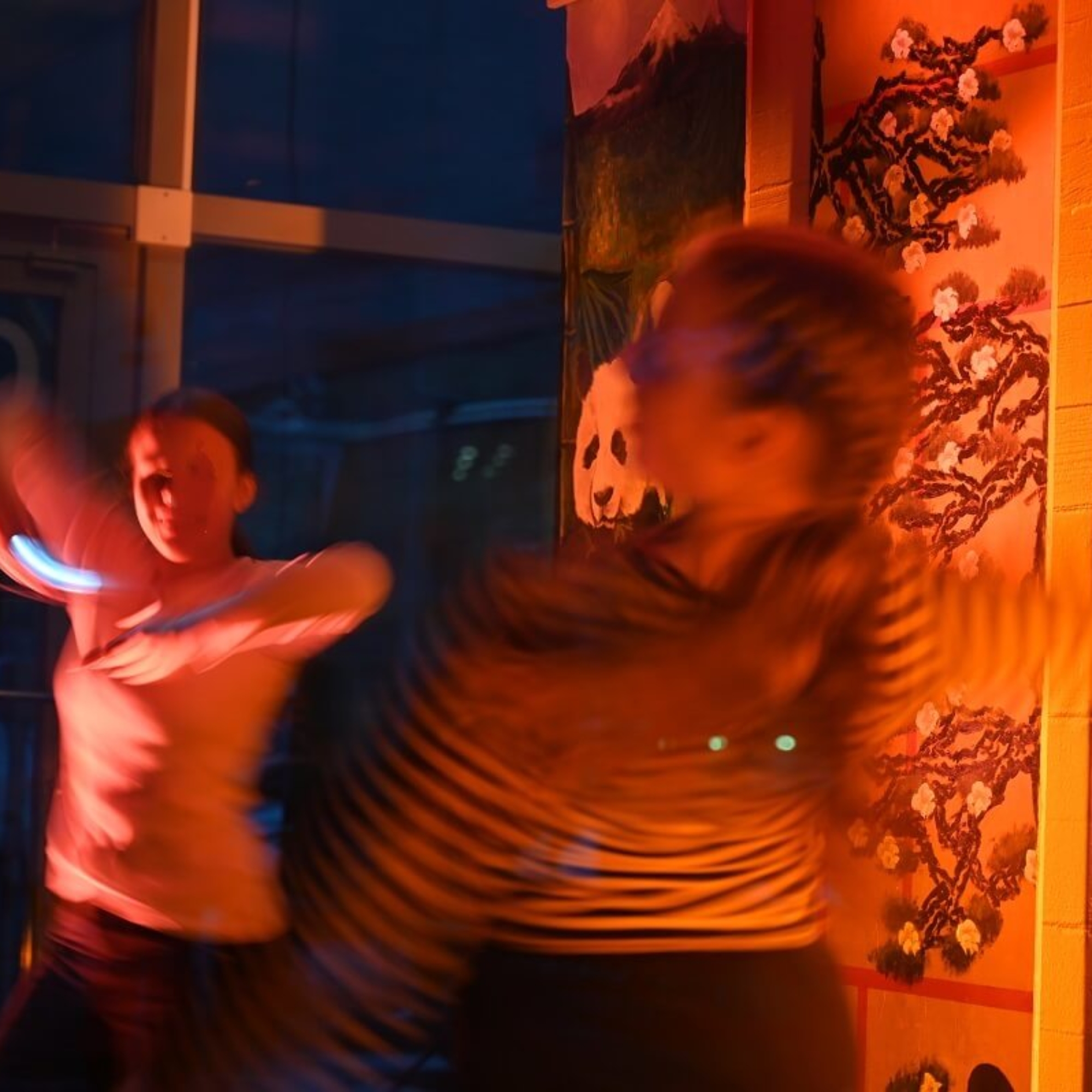 Kaksi tanssivaa tyttöä oranssissa valossa.