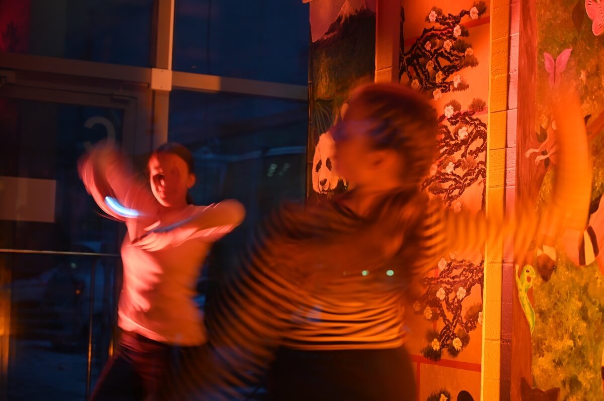 Kaksi tanssivaa tyttöä oranssissa valossa.