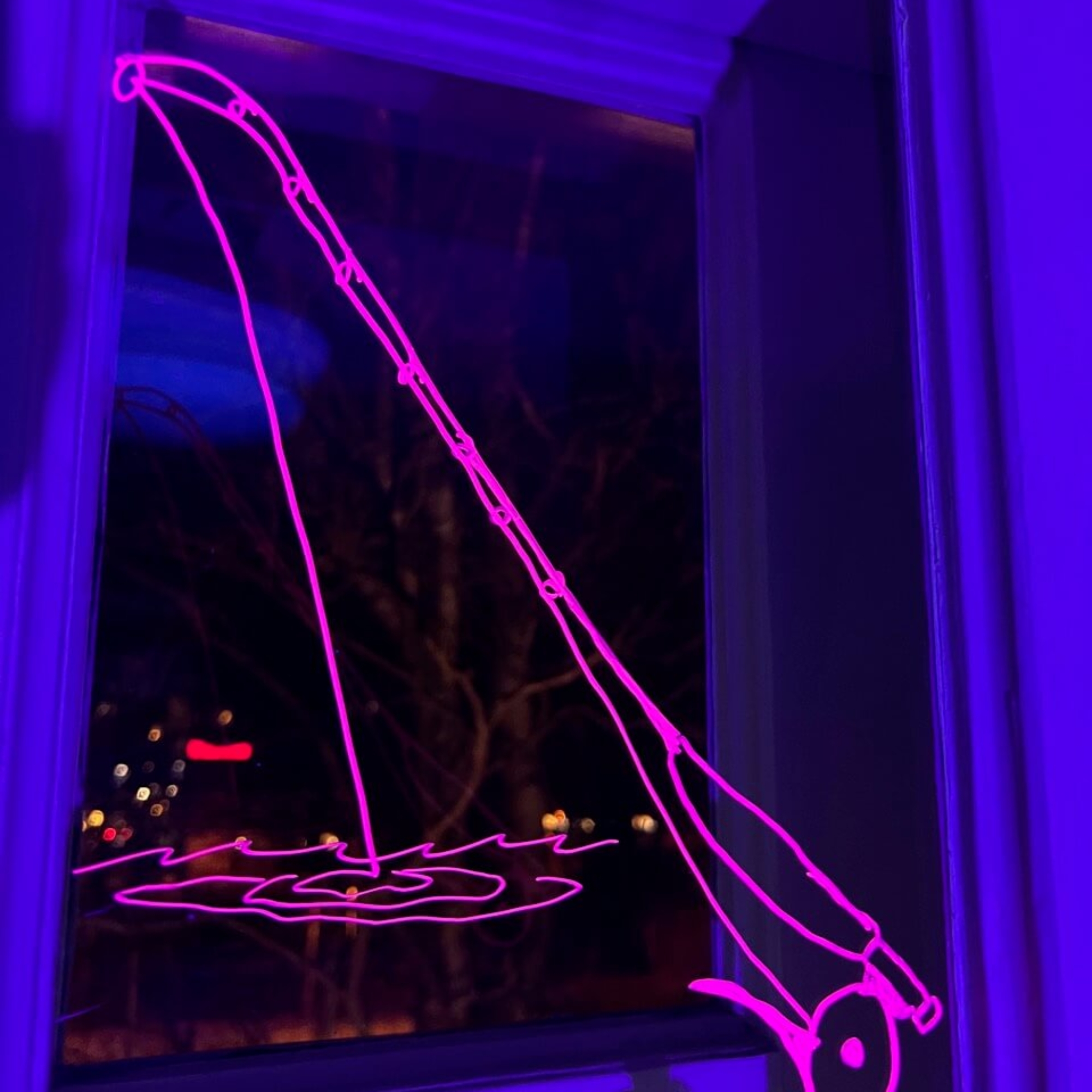UV-valolla valaistu onkivapaa esittävä piirros ikkunassa.