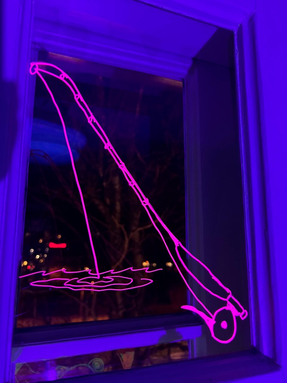 UV-valolla valaistu onkivapaa esittävä piirros ikkunassa.