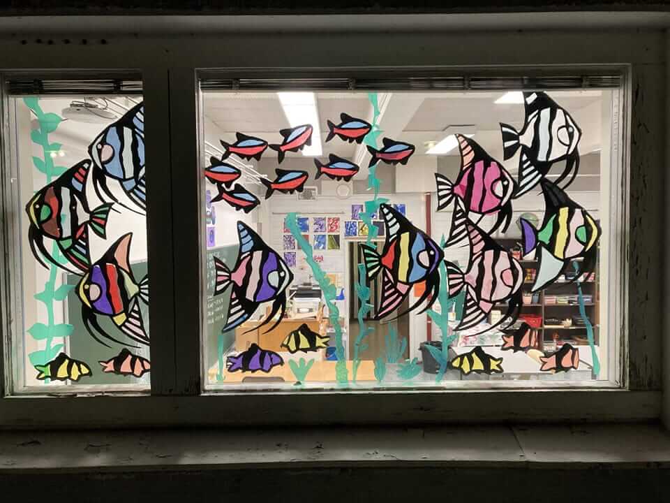 Värikkäitä maalattuja kaloja kuvataidekoulun ikkunassa.