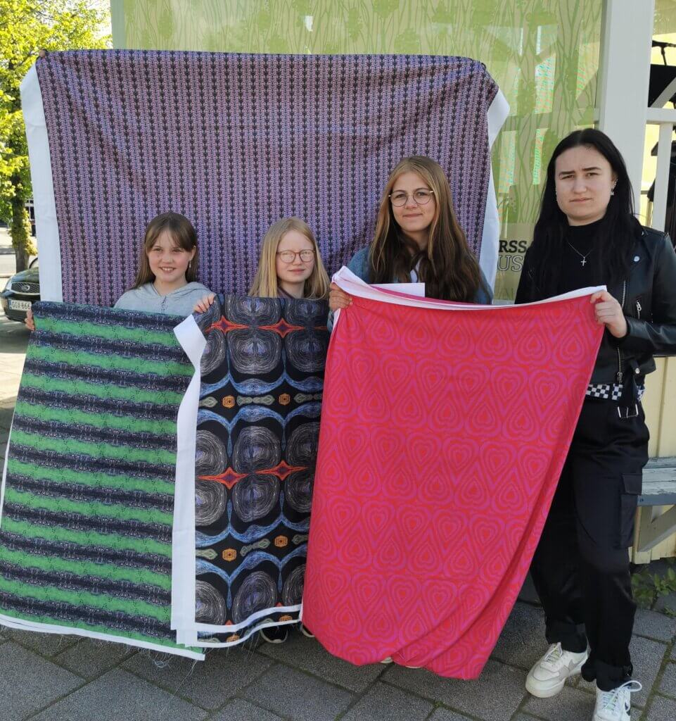 Neljä nuorta esittelemässä suunnittelemiaan kangaskuoseja Forssan torilla.