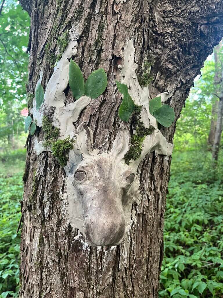 Puun runkoon savesta tai vastaavasta massasta tehty kolmiulotteinen taideteos, joka esittää hirven päätä.