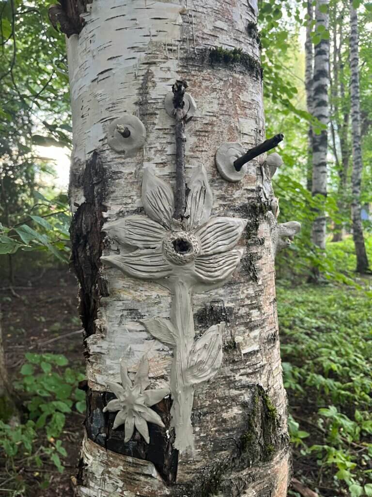 Puun runkoon savesta tai vastaavasta massasta tehty kolmiulotteinen taitdeteos, joka esittää kukkaa.